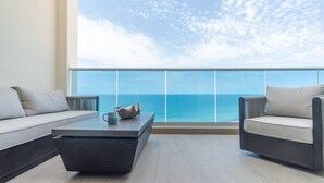 A balcony with a view of the ocean, a sofa, a chair, and a coffee table. - Amazing Condo by the Beach Encantame W1203 (Puerto Peñasco)