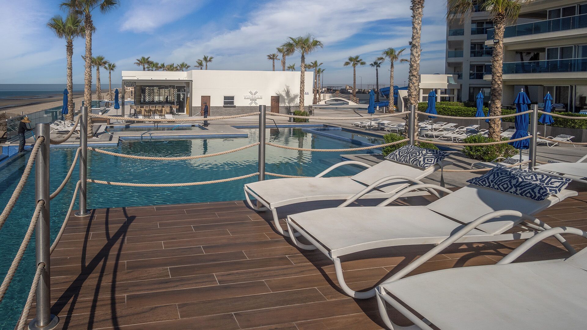 Un espace piscine avec des chaises longues et des palmiers.