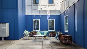 Ein Innenhof mit blauer Wand, einem weißen Briefkasten und einem Metalltisch mit Stühlen.