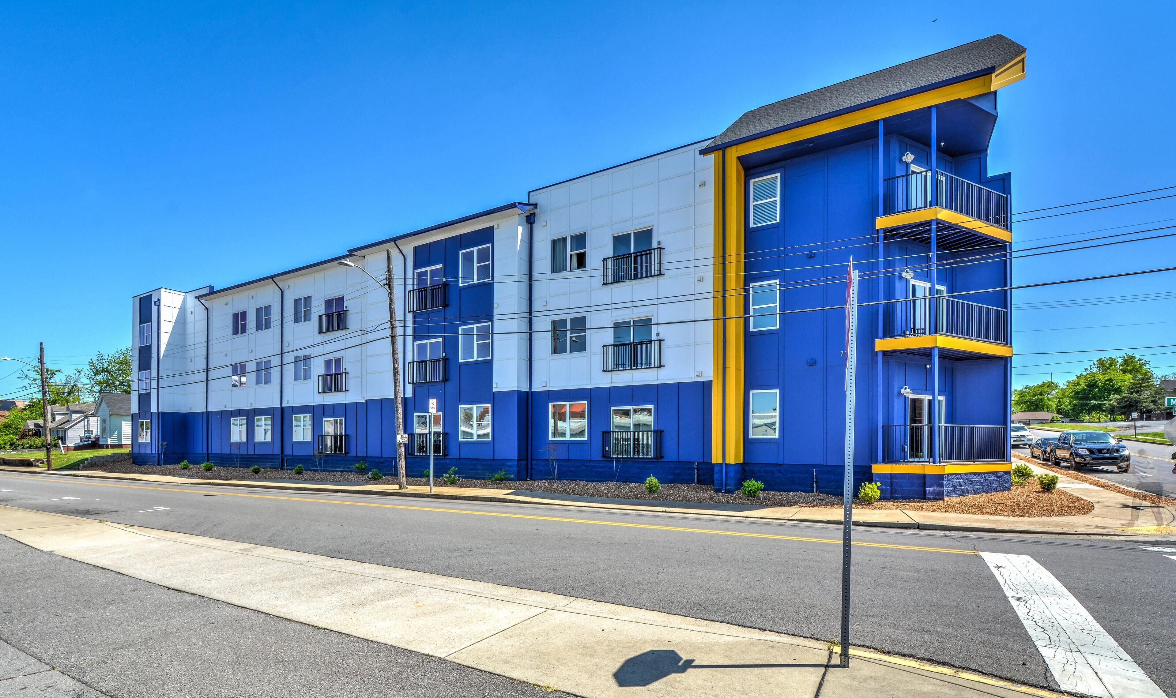 A multi-story building with a blue and white facade, featuring balconies and multiple windows.