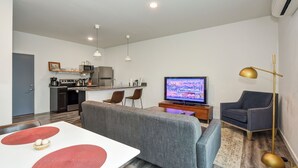 Ein modernes Wohnzimmer mit Fernseher, Sofa und Essbereich.