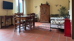 A room with a dining table, chairs, a TV, a cabinet, a bed, and a window. - Marciaga, rustic in ancient hamlet (Veneto)