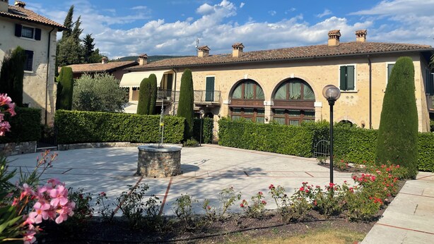 A courtyard with a stone fountain, neatly trimmed hedges, and a building with arched windows and a tiled roof. - Marciaga, rustic in ancient hamlet (Veneto)