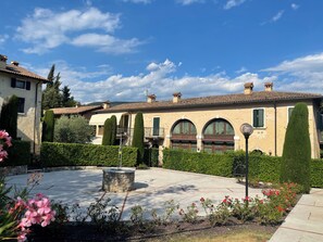 A courtyard with a stone fountain, neatly trimmed hedges, and a building with arched windows and a tiled roof. - Marciaga, rustic in ancient hamlet (Veneto)