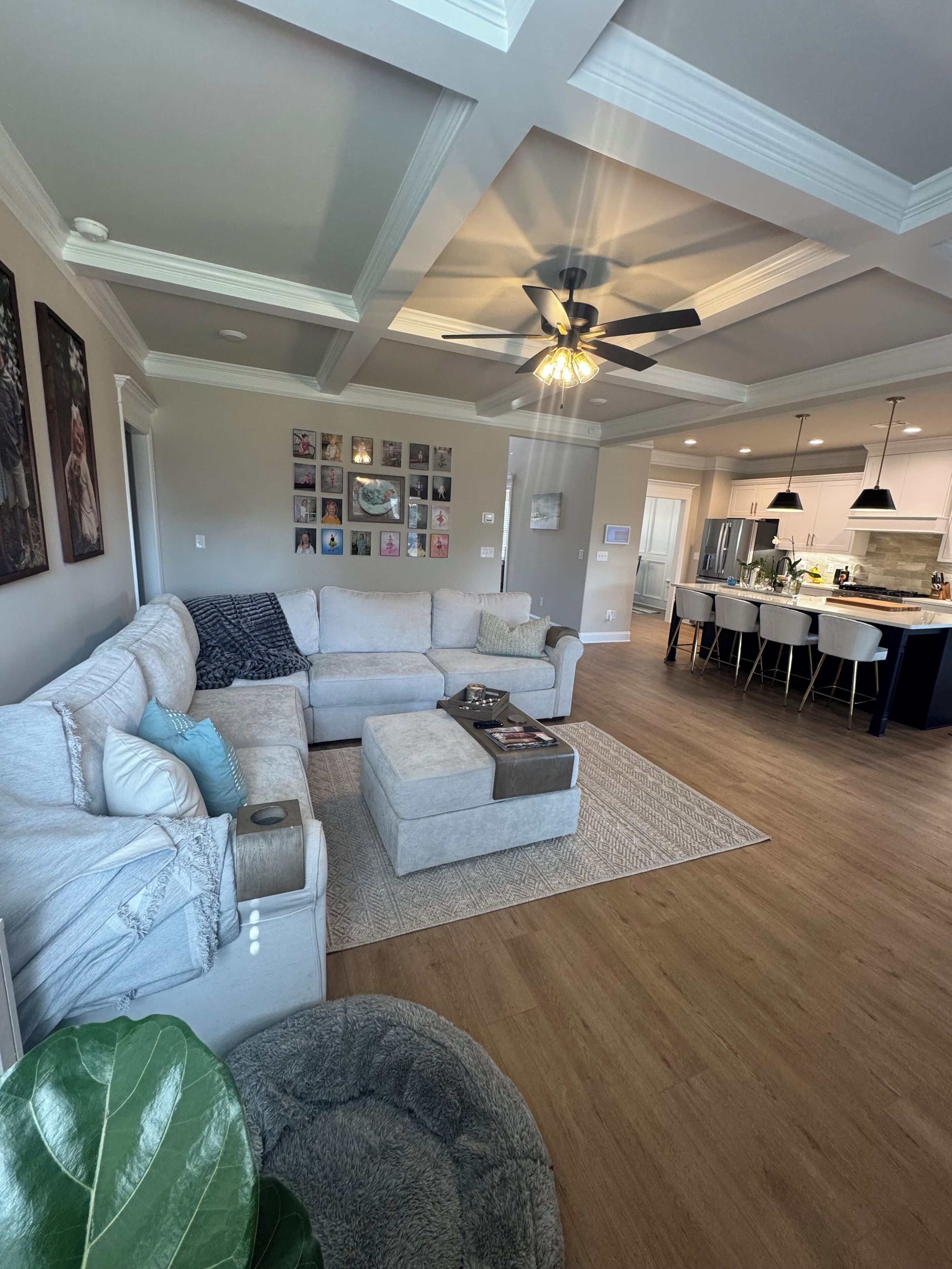 A spacious living room with a large sectional sofa, a coffee table, and a dining area with a kitchen in the background.
