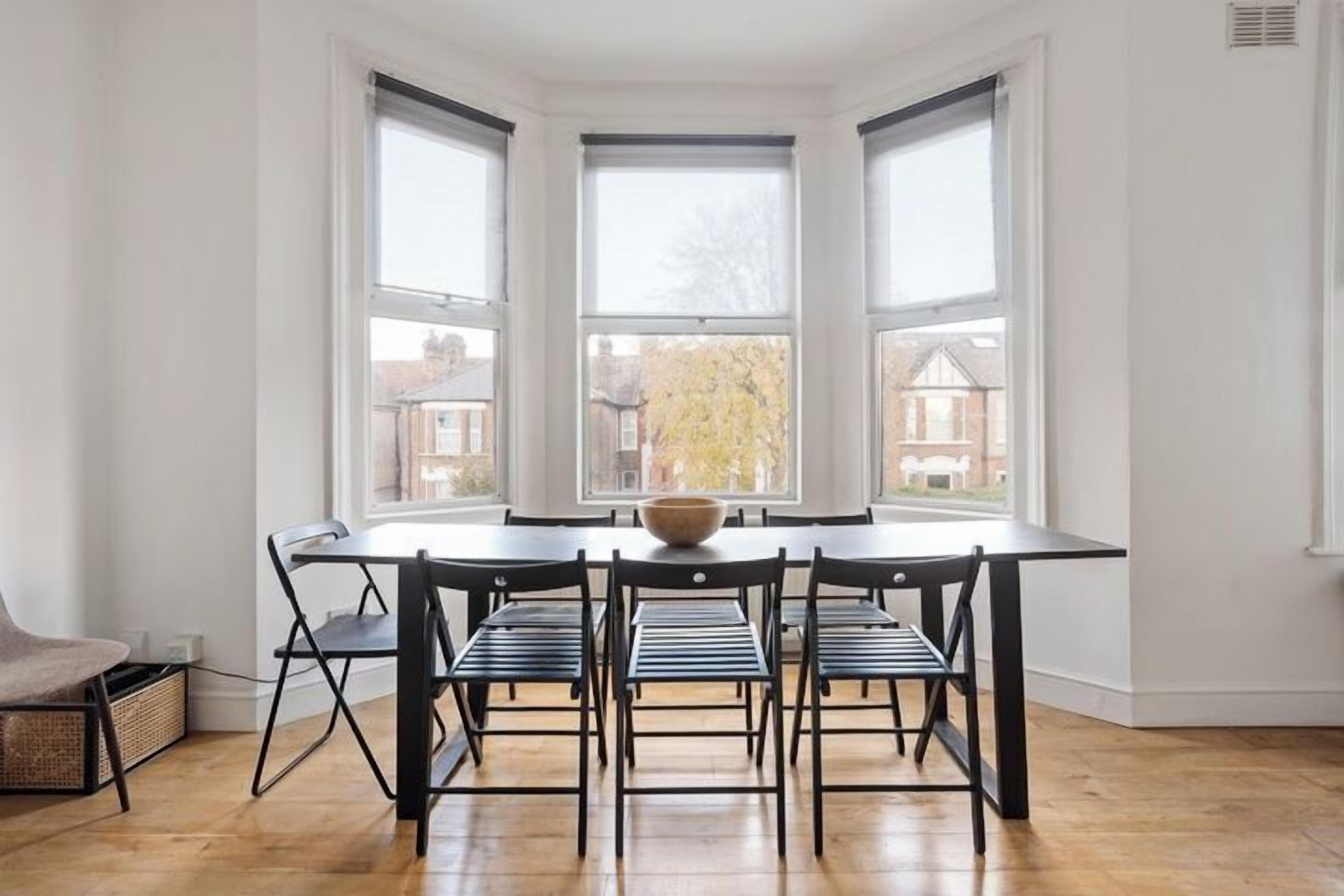 Un espace repas comprenant une table ronde, six chaises et un grand saladier au centre.