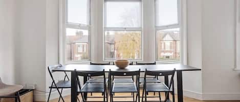 Un comedor con una mesa redonda, seis sillas y un bol en el centro.