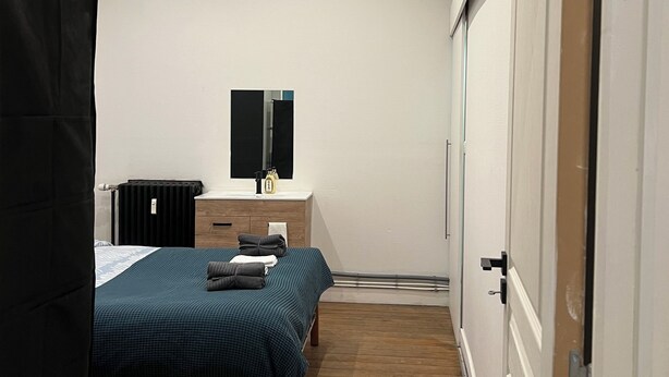 A bedroom with a bed, bedside table, radiator, and a door. - Nice 1-bedroom apartment in Namur (Namur)
