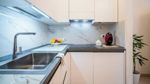 A modern kitchen with a stainless steel sink, a marble countertop, and a fruit bowl.