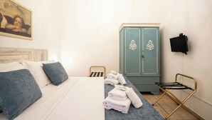 A bedroom with a bed, a blue cabinet, a TV, and a chair.