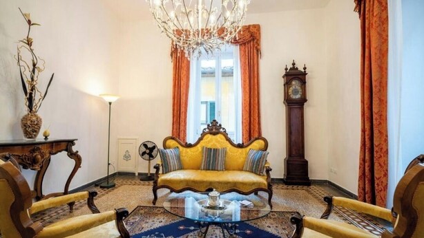 A room with a yellow sofa, a round glass coffee table, and a wooden floor.