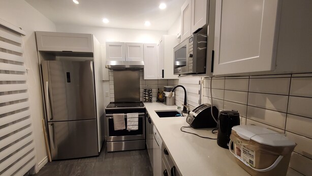 A modern kitchen with stainless steel appliances, a microwave, and a sink. - Superb apartment near Longueuil metro station (Longueuil)