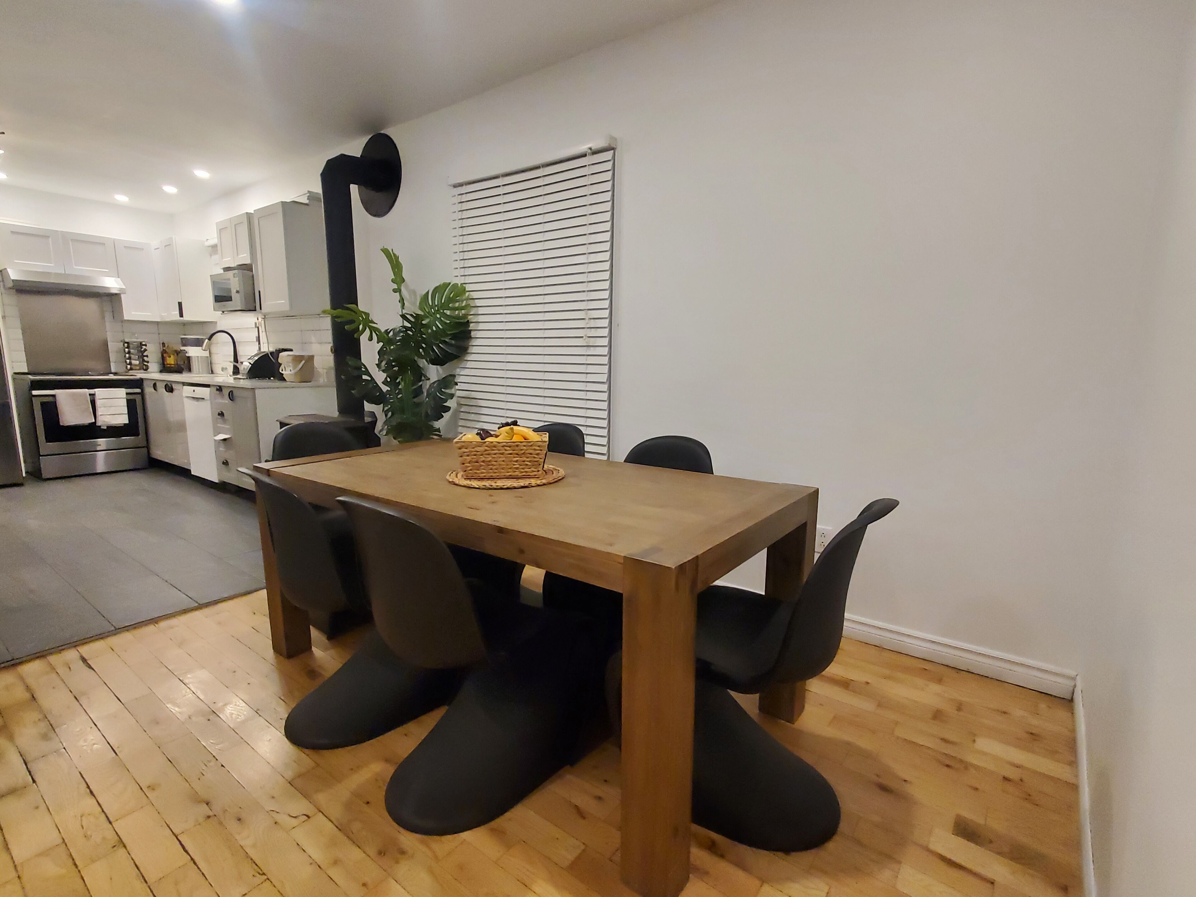 A modern kitchen with white cabinets, a wooden dining table, and black chairs.