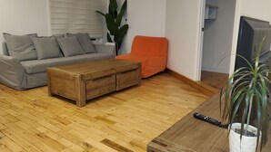 A living room with a grey sofa, an orange armchair, a wooden coffee table, and a potted plant. - Superb apartment near Longueuil metro station (Longueuil)