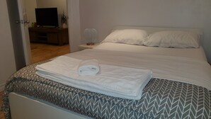 A neatly made bed with a patterned bedspread, a rolled towel, and a wall-mounted zebra print. - Superb apartment near Longueuil metro station (Longueuil)