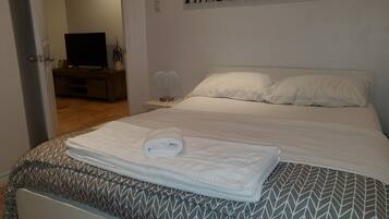 A neatly made bed with a patterned bedspread, a rolled towel, and a wall-mounted zebra print.