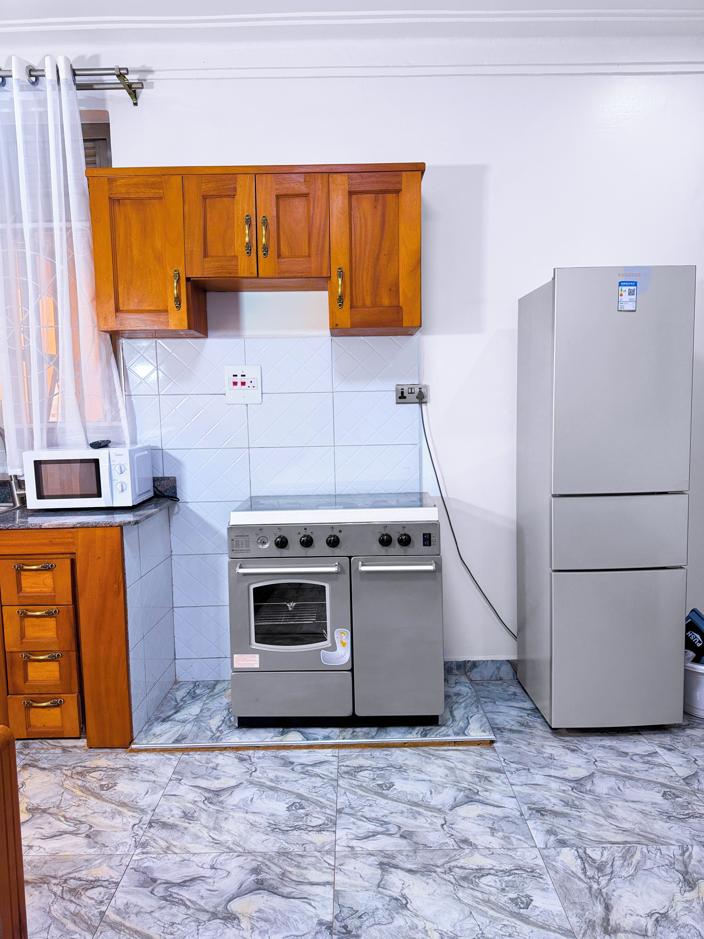 A kitchen with wooden cabinets, a stainless steel oven, a microwave, and a refrigerator.