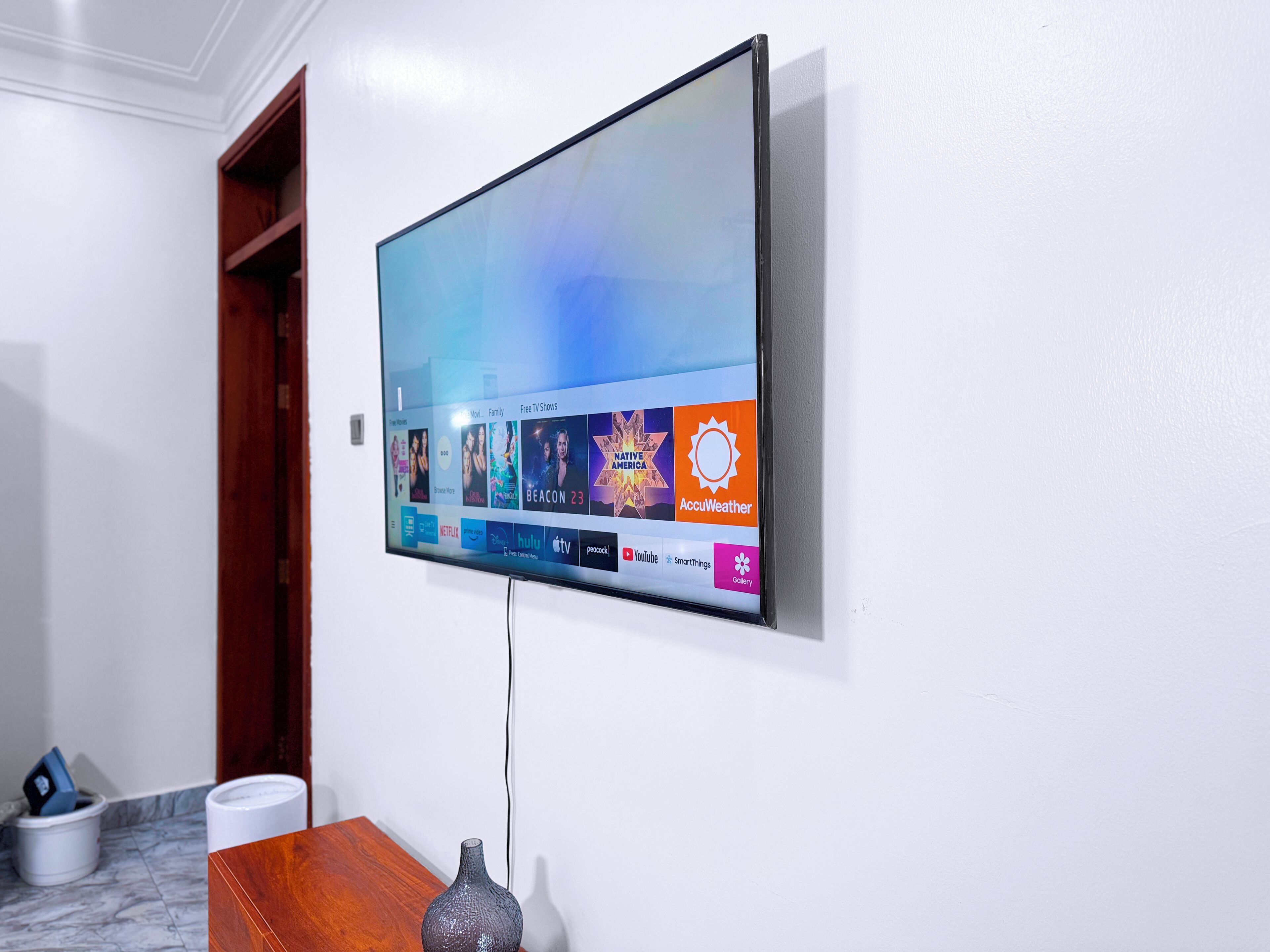 A flat-screen TV mounted on a white wall displaying various streaming services.