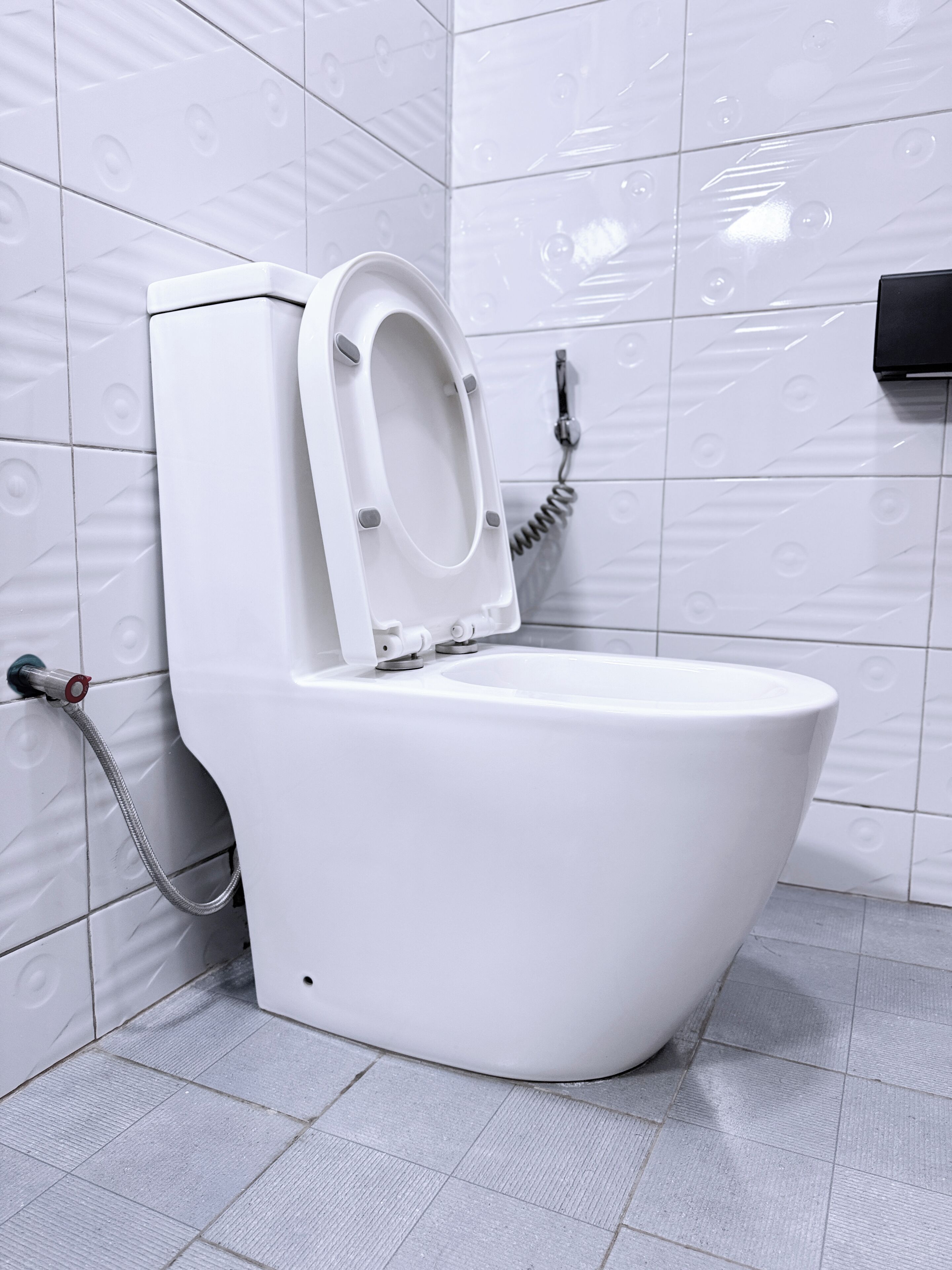 A white toilet with a closed seat, a flush handle, and a water tank.