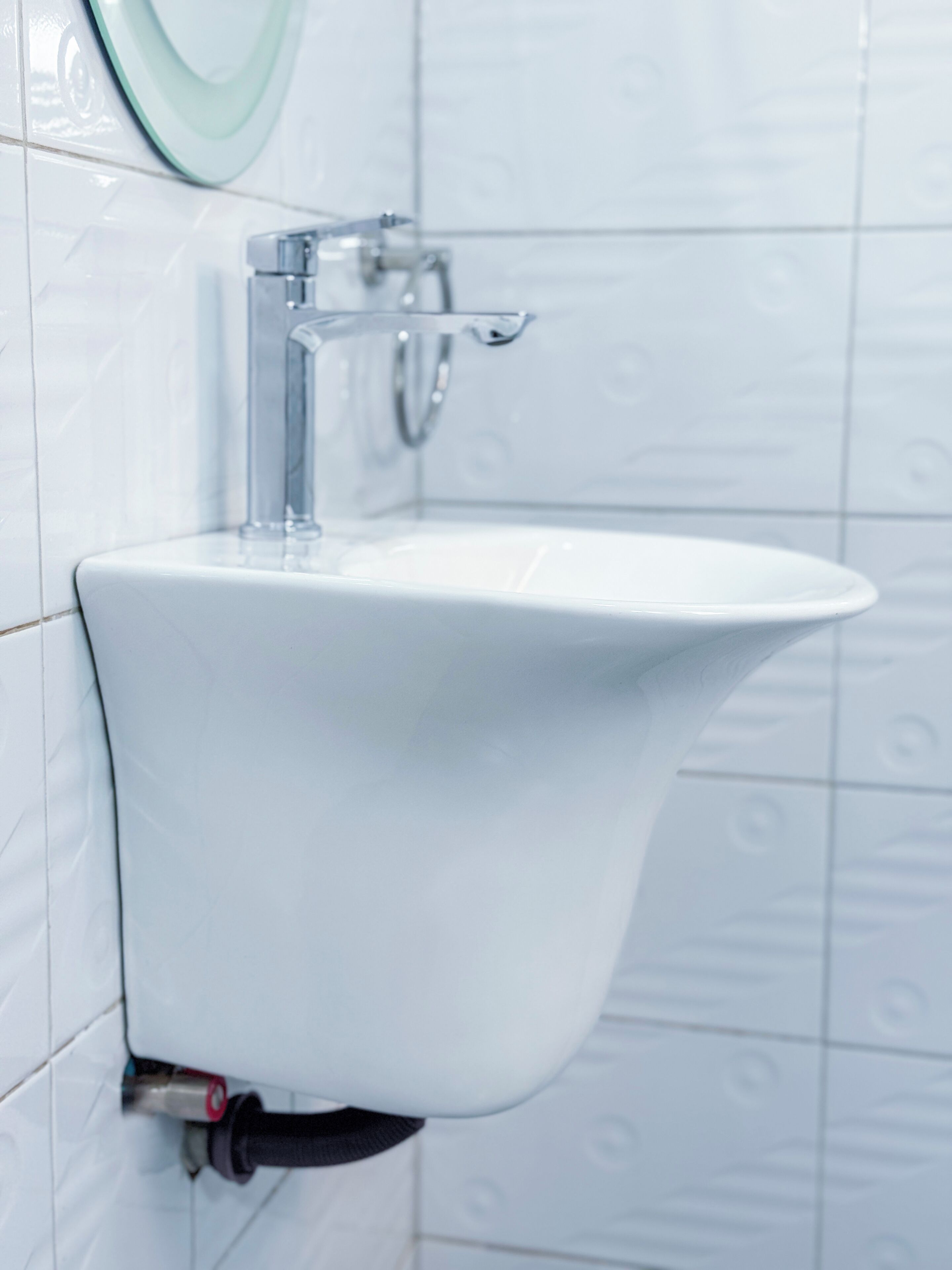 A white pedestal sink with a modern faucet and a soap dispenser.