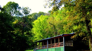 A cabin with a porch, surrounded by dense trees.