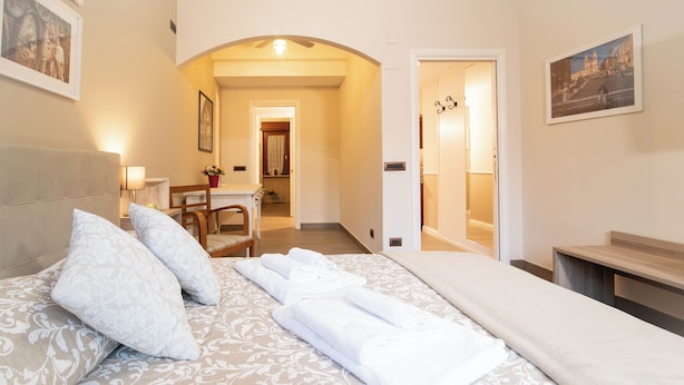 A hotel room with a large bed, a desk, and a chair. There is a door leading to a bathroom and a hallway. - Caffarella Vacanze, comfort and relaxation a few minutes from the heart of Rome (Roma)