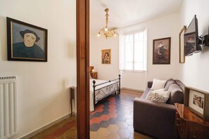 A room with a bed, a sofa, a chandelier, and artwork on the walls.