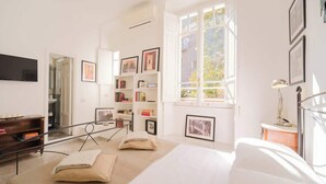 A bright room with a bed, bookshelves, and a TV. - BuddyRent - Vatican Domus - 4 ospiti (Rome)