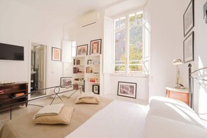A bright room with a bed, bookshelves, and a TV.