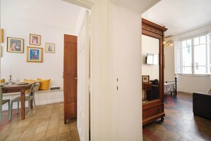 Ein Essbereich mit einem Holztisch und Stühlen, einer Bank mit gelben Kissen sowie einer Wand mit gerahmten Bildern.