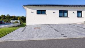 A modern building with a flat roof, large windows, and a paved driveway. - M&M AusZeit in Schwabenländle in Winterlingen (Winterlingen)