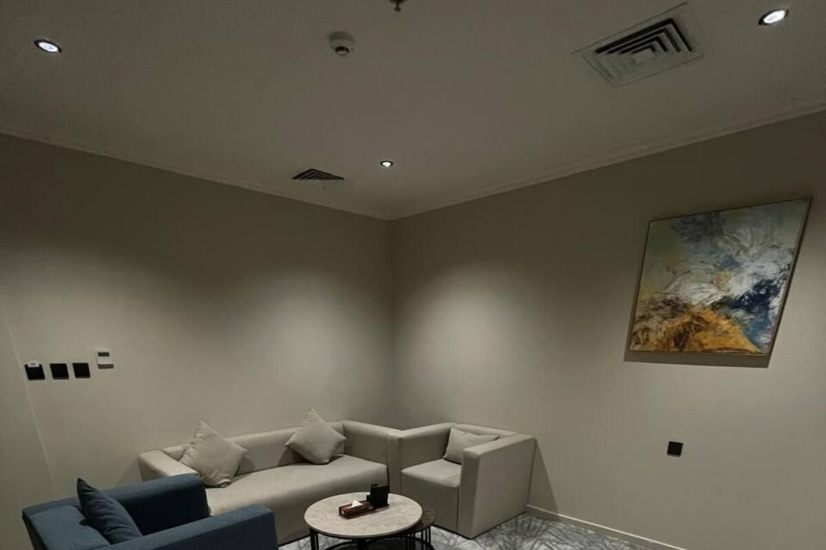 Una sala de estar moderna con una alfombra gris estampada, un sofá azul y otro sofá gris, además de una mesa de centro redonda.