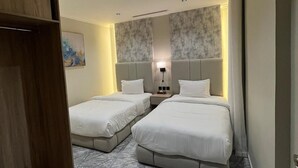 A hotel room with two beds, a wardrobe, a painting on the wall, and a patterned carpet. - Villa park (Al Khobar)