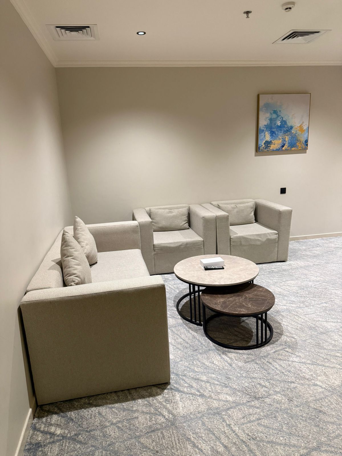 A modern living room with a sectional sofa, a round coffee table, and a painting on the wall.