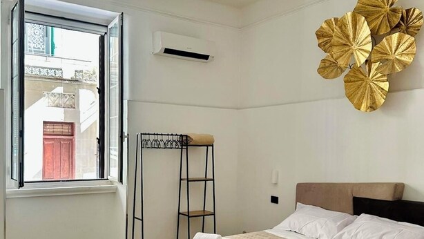 Un dormitorio con cama, ventana, equipo de aire acondicionado, escalera y un adorno de pared.