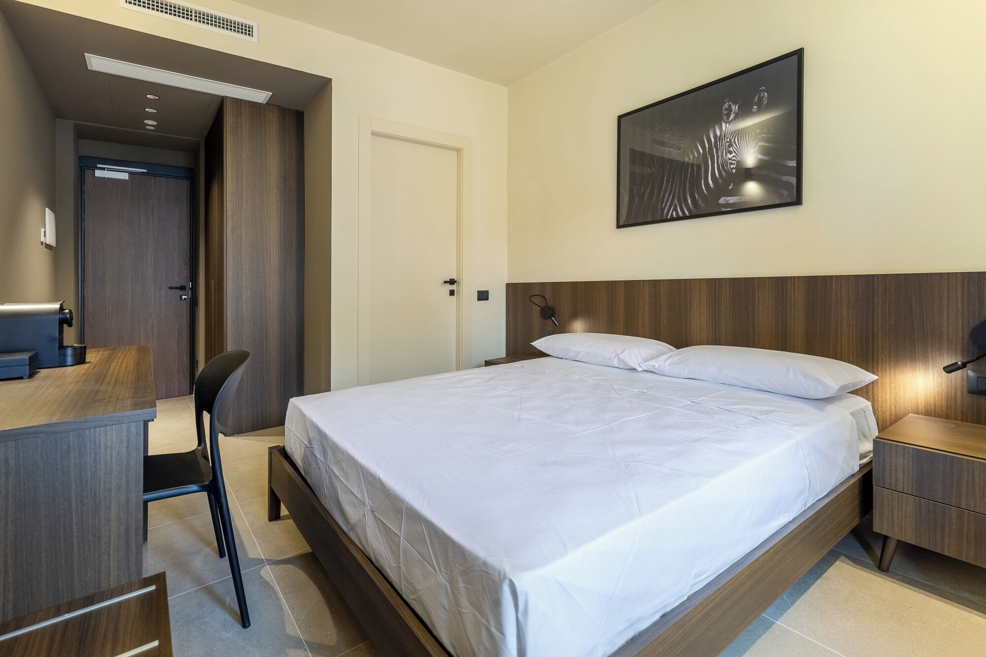 Una camera d'albergo moderna con un letto grande, una scrivania e una sedia.