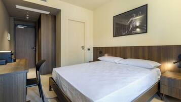 Una camera d'albergo moderna con un letto grande, una scrivania e una sedia.