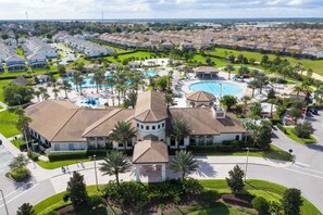 A residential area with a large swimming pool, multiple houses, and a central building with a circular tower.