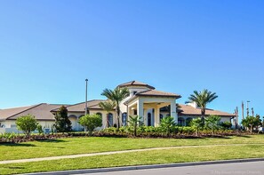 A large, single-story house with a central dome, surrounded by a well-maintained lawn and palm trees.