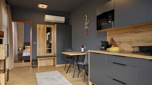 A modern kitchen with a wooden countertop, a built-in microwave, and a dining area with a bench and chairs. - Villa Olea (Tihany)