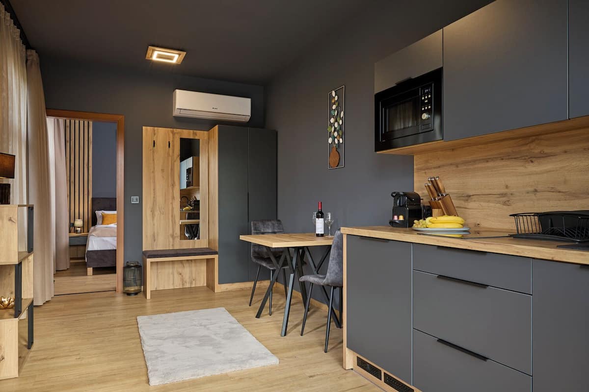 Une cuisine moderne dotée d’un plan de travail en bois, d’un four à micro-ondes encastré et d’un coin repas avec un banc et des chaises.