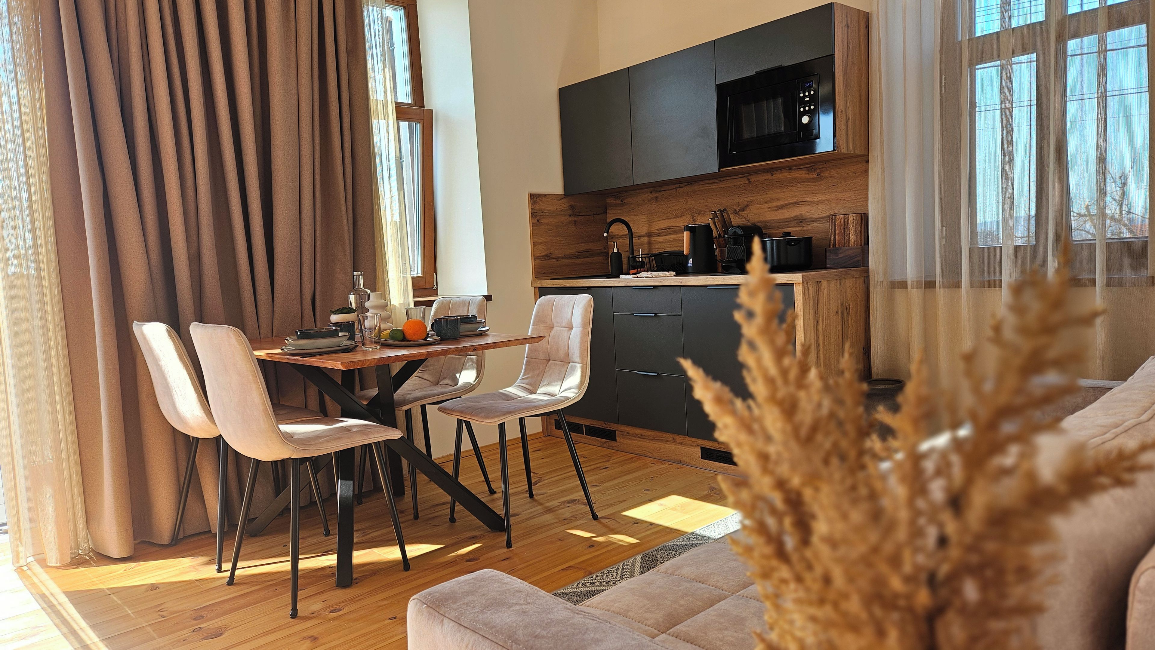 A modern kitchen with a microwave, wooden cabinets, and a dining area with a table and chairs.