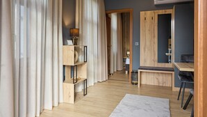 A modern hotel room with wooden flooring, a desk, a chair, a mirror, and a bookshelf. - Villa Olea (Tihany)