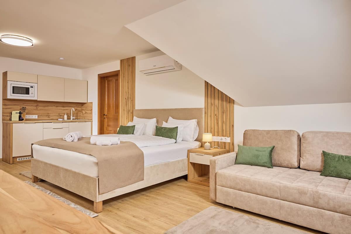 Une chambre moderne comprenant un lit, une table de chevet, un canapé et un coin cuisine.