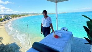 A room with a bed, a towel, and a bottle, overlooking a beach and ocean. - Ultra Infinity Hotel (Cabarete)