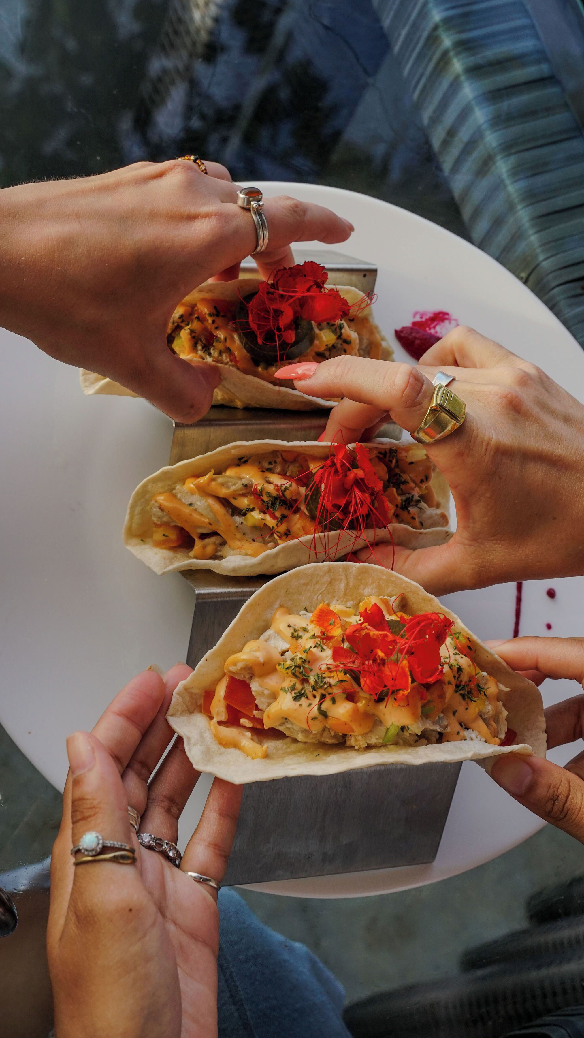 Trois personnes tenant des tacos et une assiette blanche.
