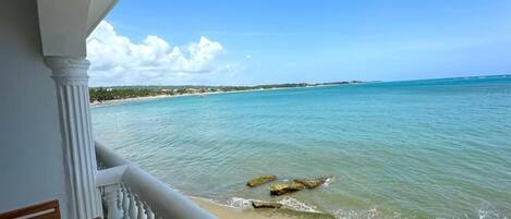 A balcony with a view of the beach and ocean.