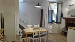 A dining area with a wooden table and white chairs, a window with bars, a staircase, and a fireplace. - THE ROOFTOP LOFT entire apartment in the center of Milan in Porta Venezia (Milano)