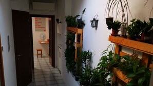 A narrow hallway with a tiled floor, wooden railings, and potted plants on shelves. - THE ROOFTOP LOFT entire apartment in the center of Milan in Porta Venezia (Milano)