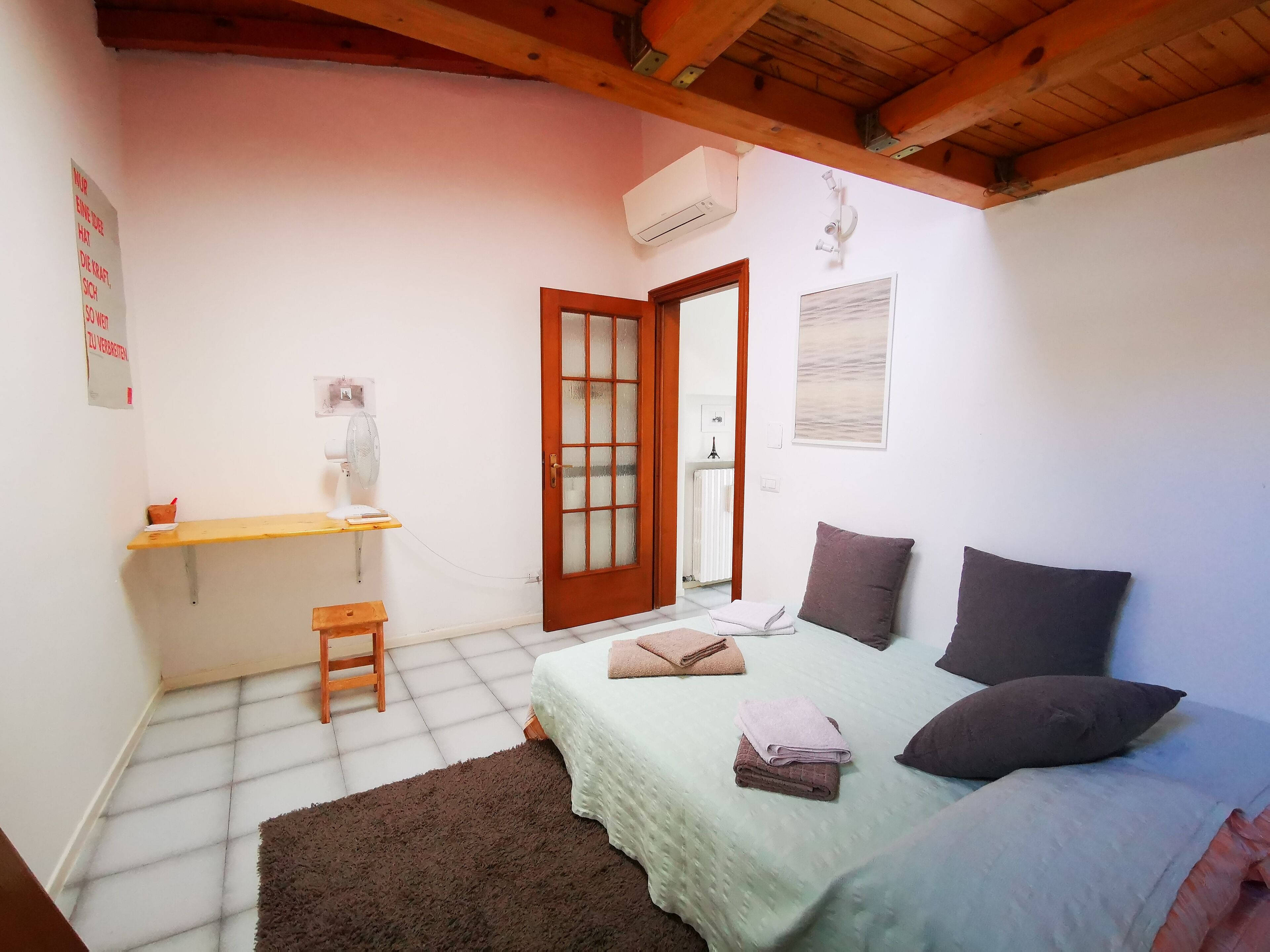 A bedroom with a bed, a desk, a chair, and a door.